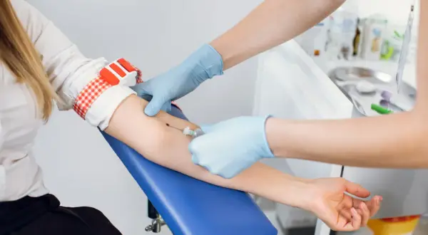 Pobieranie krwi do badań na czczo. Pielęgniarka w rękawiczkach pobiera krew z żyły pacjentki.