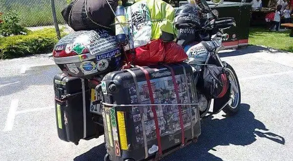 Motocykl z bagażami, gotowy na wyprawę. Widać walizki, torby i kask. To wszystko, co zabrać na wyprawę motocyklową.