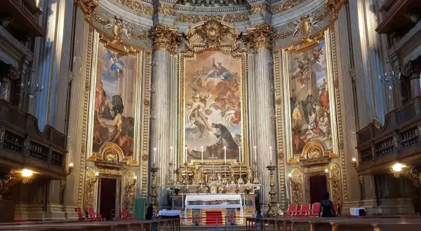 Interno della chiesa di Sant'Ignazio di Loyola, con affreschi barocchi, altare dorato e panche in legno.
