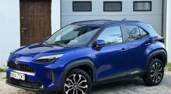 Niebieski Toyota Yaris Cross Hybrid 2022 na tle garażu. Sprawdź jego atrakcyjną cenę!