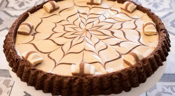 Torta Kinder Bueno con decorazione a ragnatela di cioccolato e pezzi di wafer.