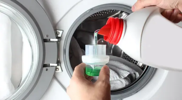 Versare il detersivo liquido nella capsula dosatrice, per sapere quanto detersivo mettere in lavatrice.