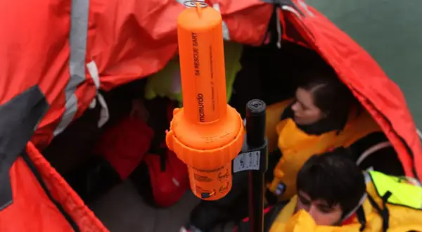 Arancione transponder navi SART McMurdo in una zattera di salvataggio con persone con giubbotti di salvataggio.