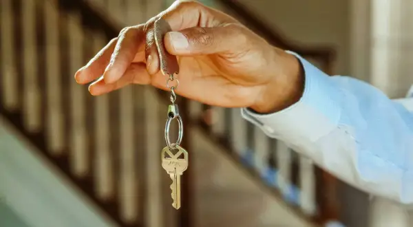 Chiave di casa tenuta in mano, simbolo di un immobile intestato ad un solo coniuge in comunione dei beni.