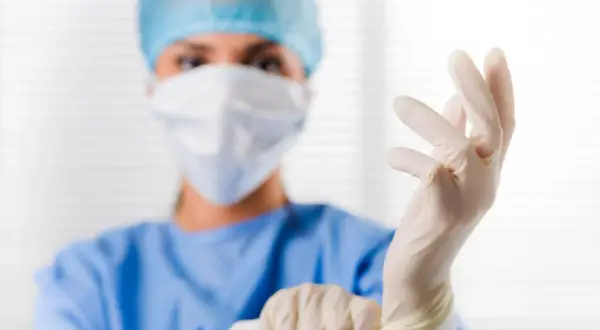 Ärztin zieht Handschuhe an. Der PSA-Wert ist wichtig für die Sicherheit.