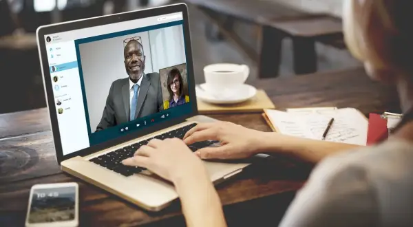 Kobieta prowadzi rozmowę przez Skype z dwoma współpracownikami.