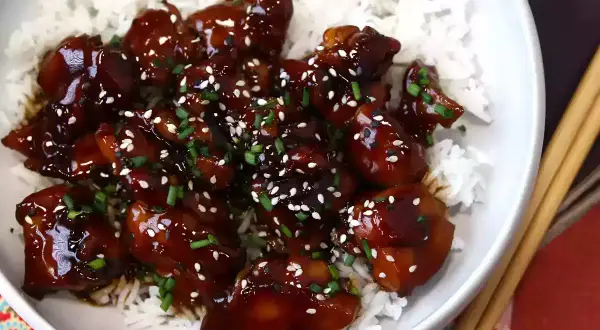Kyckling i glansig teriyakisås med sesamfrön och gräslök, serverad över ris. Ett enkelt teriyakisås recept att prova.