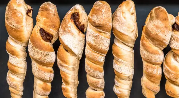Goldbraunes Stockbrot ohne Hefe, mit dunkler Füllung, auf schwarzem Hintergrund.