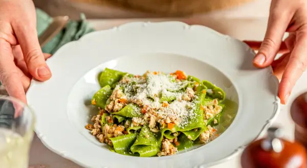Grüne Bandnudeln mit einem herzhaften ragu bianco, bestreut mit Parmesan.