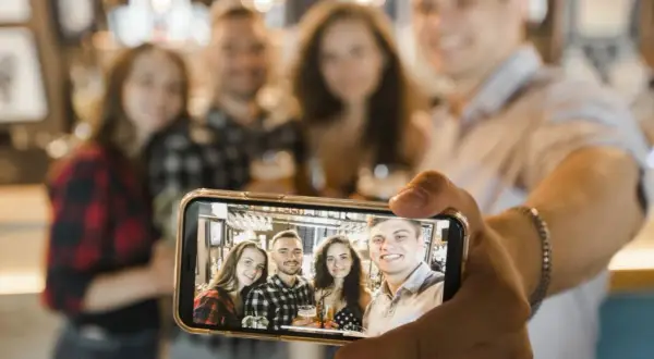 Grupa przyjaciół robi sobie zdjęcie grupowe telefonem. Oto jak zrobić selfie telefonem, by uchwycić wspólne chwile.