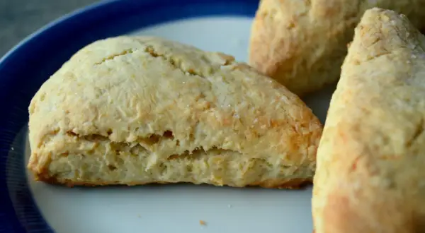 Tre gyllene scones, bakade med bakpulver, ligger på en tallrik med blå kant.