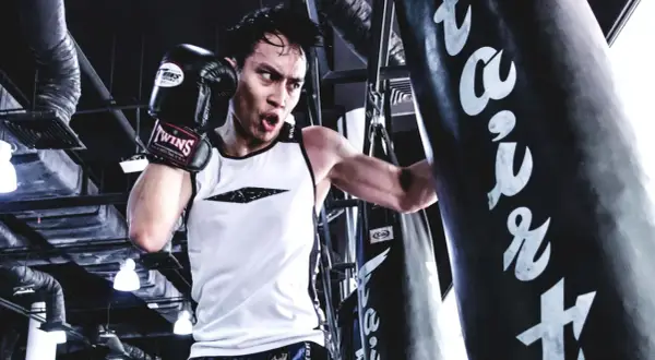 A boxer trains intensely, focusing on his boxing breathing as he punches a heavy bag.