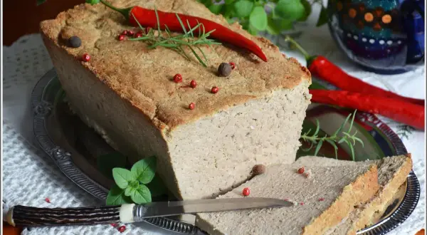 Pyszny pasztet mieszany drobiowo-wieprzowy, udekorowany papryczką chili i ziołami, gotowy do podania na kromce chleba.