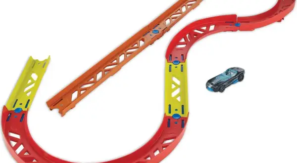 Tor wyścigowy Hot Wheels z czerwonymi zakrętami, żółtym mostkiem i pomarańczowym odcinkiem prostym. Obok czarny samochodzik.