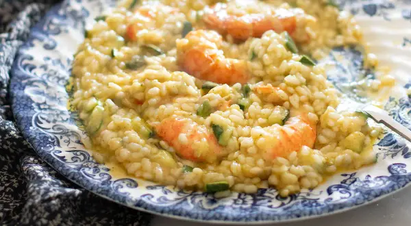 Risotto cremoso con zucchine e gamberetti, un piatto estivo da gustare.