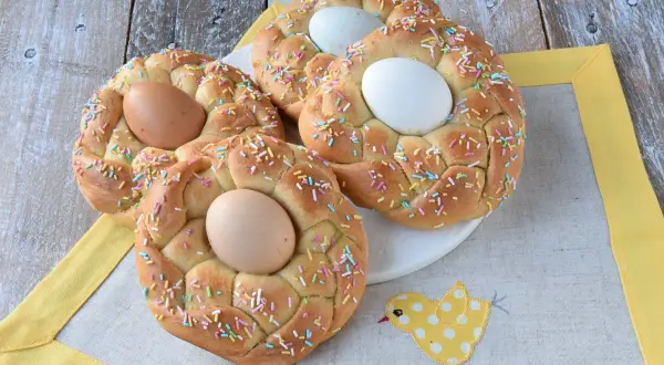 Nidi di Pasqua intrecciati, decorati con codette colorate e uova, pronti per la festa.