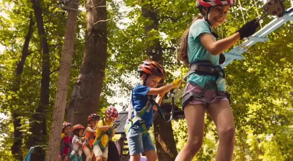 Dzieci w kaskach pokonują park linowy, świetna zabawa i **bieszczady atrakcje dla dzieci**.