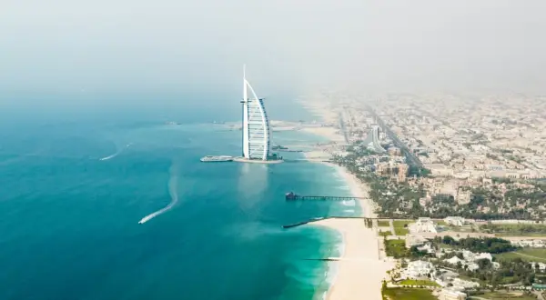 Widok z lotu ptaka na plaże w Dubaju, z charakterystycznym hotelem Burdż al-Arab i turkusową wodą.