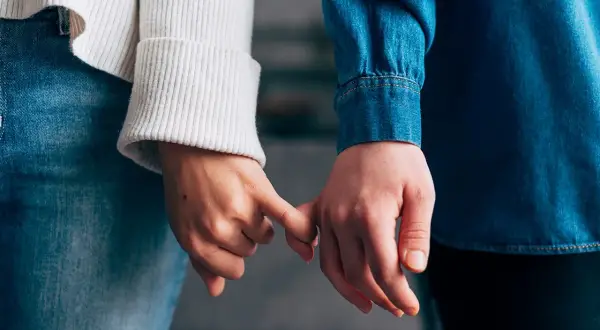 Due mani si stringono con il mignolo, simbolo di un legame che si rinnova dopo un periodo di **lasciarsi e riprendersi psicologia**.