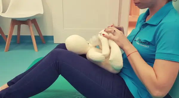 Terapeuta ćwiczy pozycję do karmienia butelką z pluszowym niemowlakiem.
