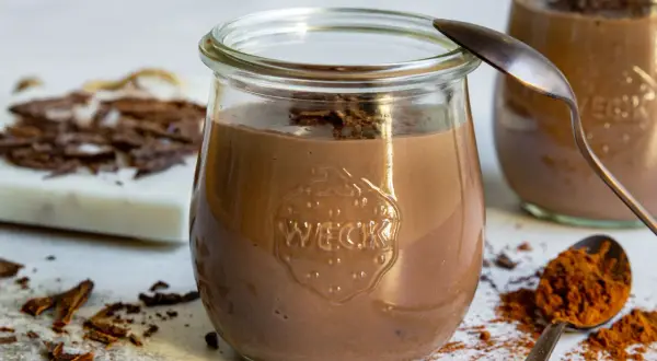 Cremiger Schokopudding, perfekt zum schokopudding selber machen. Serviert in einem Weckglas, garniert mit Schokostückchen.