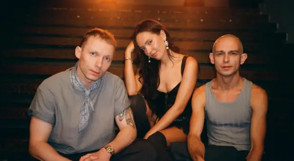 Trzy osoby siedzą na schodach: dwóch mężczyzn i kobieta.