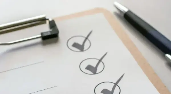 Klemmbrett mit Stift und abgehakten Punkten auf einer Checkliste.