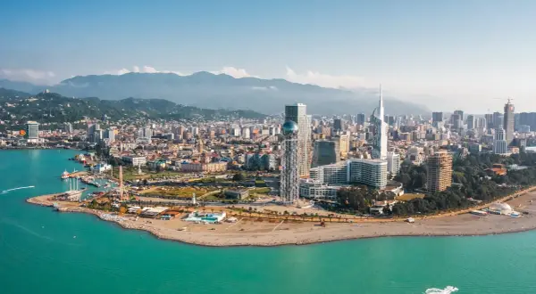 Widok na nowoczesne budynki Batumi i turkusowe morze. W tle góry, idealny batumi klimat do wypoczynku.