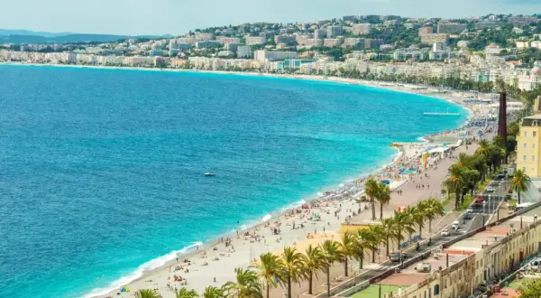 Idealne lazurowe wybrzeże wczasy all inclusive: plaża pełna ludzi, palmy i turkusowe morze.