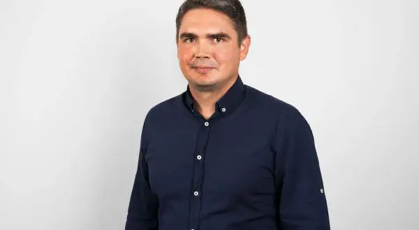 Portret mężczyzny w granatowej koszuli na jasnym tle.