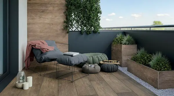 Drewnopodobne płytki na balkon tworzą przytulną atmosferę. Wygodny fotel, pufy i rośliny zapraszają do relaksu.
