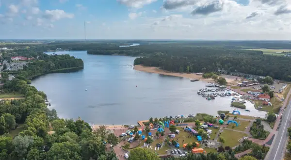 Widok na jezioro Otmuchowskie z lotu ptaka. Widać plażę, przystań jachtową, las i miasteczko z atrakcjami.