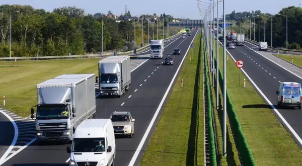 Ciężarówki i samochody osobowe na drodze dwupasmowej. Wyprzedzanie na drodze dwupasmowej jest w pełni widoczne.