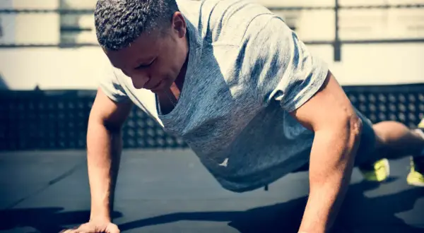 Un homme en plein effort, réalisant des burpees. Son corps est gainé, prêt à repousser le sol.