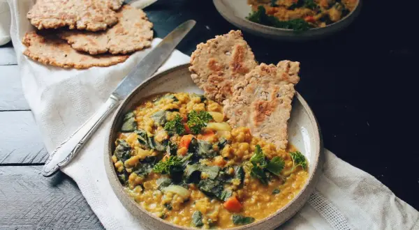 Un plat réconfortant de lentille corail recette, garni de persil frais et servi avec des galettes croustillantes.