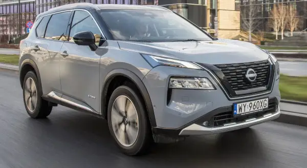 Szary Nissan X-Trail e-POWER w ruchu miejskim. Kierowca testuje jego niskie spalanie.