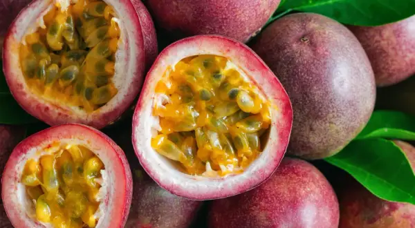 Des fruits de la passion entiers et coupés en deux, révélant leur pulpe juteuse et leurs graines noires. Un délice tropical prêt à être dégusté.