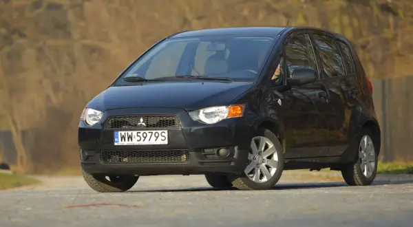 Czarny Mitsubishi Colt 1.3 na drodze, z widocznym numerem rejestracyjnym WW 5979S.