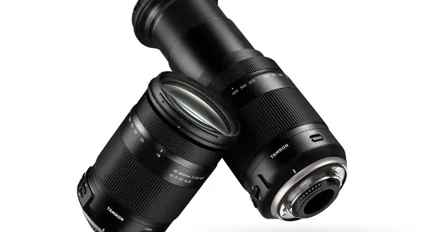 Dwa obiektywy Tamron 18-400 mm, jeden z wysuniętym zoomem, drugi z zasuniętym, unoszą się na białym tle.