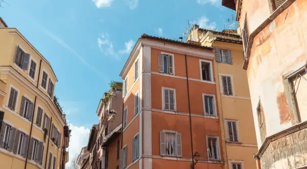 Edifici color pastello a Roma, con persiane chiuse. Il loro valore di un immobile inagibile è incerto, ma il fascino storico rimane.