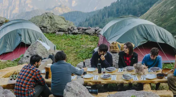 Amici in campeggio, cena all'aperto con vista monti. Un'esperienza ferdy wild indimenticabile tra tende e natura.