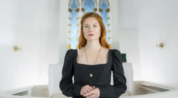 Elegancki, czarny ubiór do kościoła, z kwadratowym dekoltem i bufiastymi rękawami, podkreśla powagę chwili.