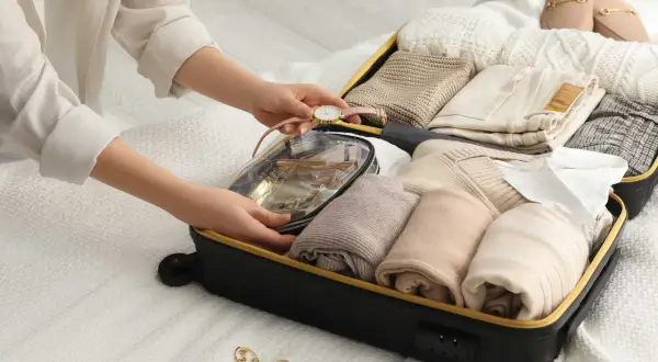 Packa smart för din resa med handbagage. En person organiserar kläder och necessär i en resväska.
