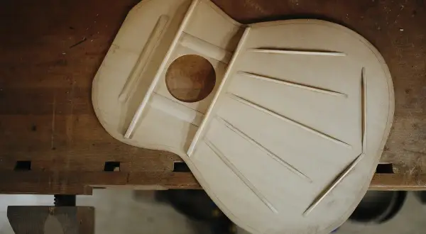 La tapa armónica de una guitarra, hecha de madera de picea, con sus varillas de refuerzo dispuestas para crear un sonido resonante.
