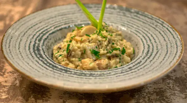 Un crémeux risotto champignon, parsemé de persil frais et garni d'une touche verte. Un délice pour les yeux et les papilles.
