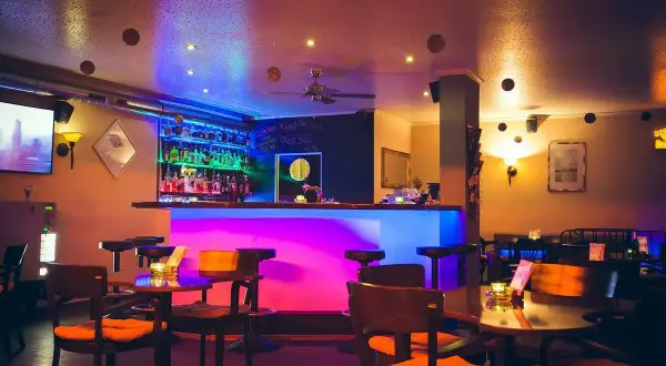 Gemütliche Bar mit bunter Beleuchtung, vielen Flaschen hinterm Tresen und Tischen. Hier kann man im "Liberté Heilbronn" entspannen.
