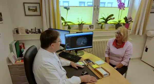 Arzt bespricht CT-Scan mit Patientin. Die Lebenserwartung bei Lungenkrebs Stadium 2 ist ein wichtiges Thema.