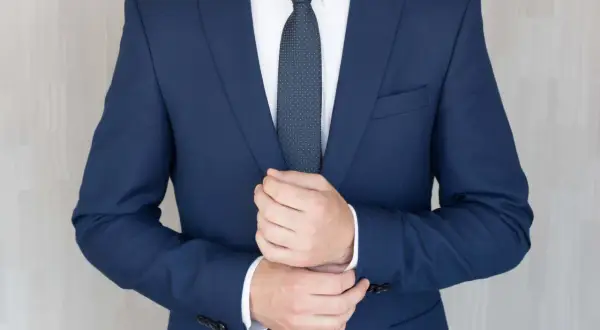 Mężczyzna poprawia mankiet granatowego garnituru na pogrzeb. Elegancki strój podkreśla powagę chwili.