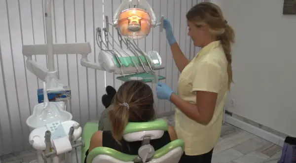 Dentystka przygotowuje znieczulenie w sprayu dla pacjentki siedzącej na fotelu.