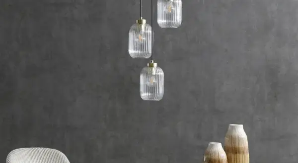 Eleganckie lampy loftowe z przezroczystego szkła wiszą nad marmurowym blatem.